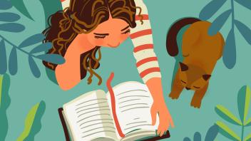 Young girl in striped short reading a book next to a cat