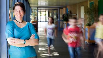 elementary principal is school hallways with students rushing by
