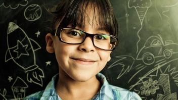 Young multiracial girl in front of blackboard with chalk drawings of science