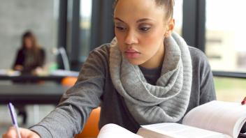young teacher reading a professional book in library and taking notes