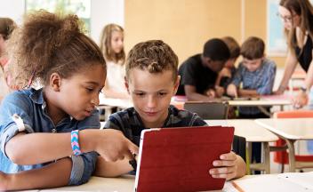 two elementary students working on tablet together in class