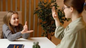 Elementary school-aged deaf student using sign language with teacher