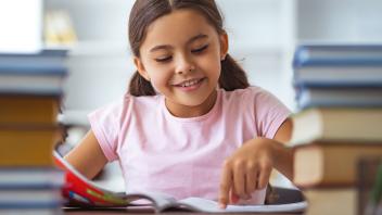 First grade girl reading book in class