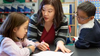 Elementary teacher working with two students on reading