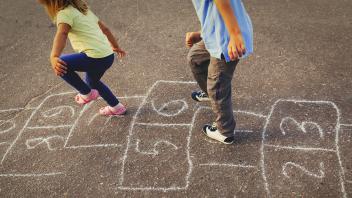 two young children jumping hopscotch outside