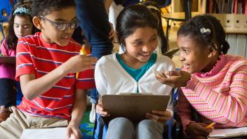 three elementary students discussing a text together in class