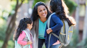 Latina mother with two elementary aged kids going to school
