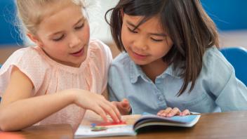 Young elementary student reading aloud to another student