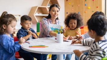 preschool teacher with kids working on writing and drawing