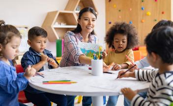 preschool teacher with kids working on writing and drawing