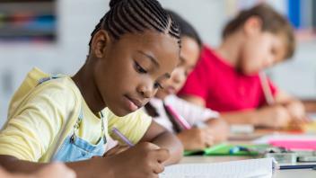 row of elementary students concentrating on writing in class