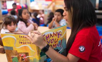 Volunteer reader doing a picture book read aloud with diverse group of kids