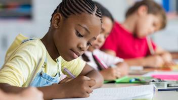 Elementary school girl at her classroom desk engaged in writing assignment