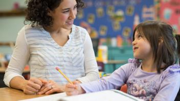 elementary teacher working one-on-one with student on her writing